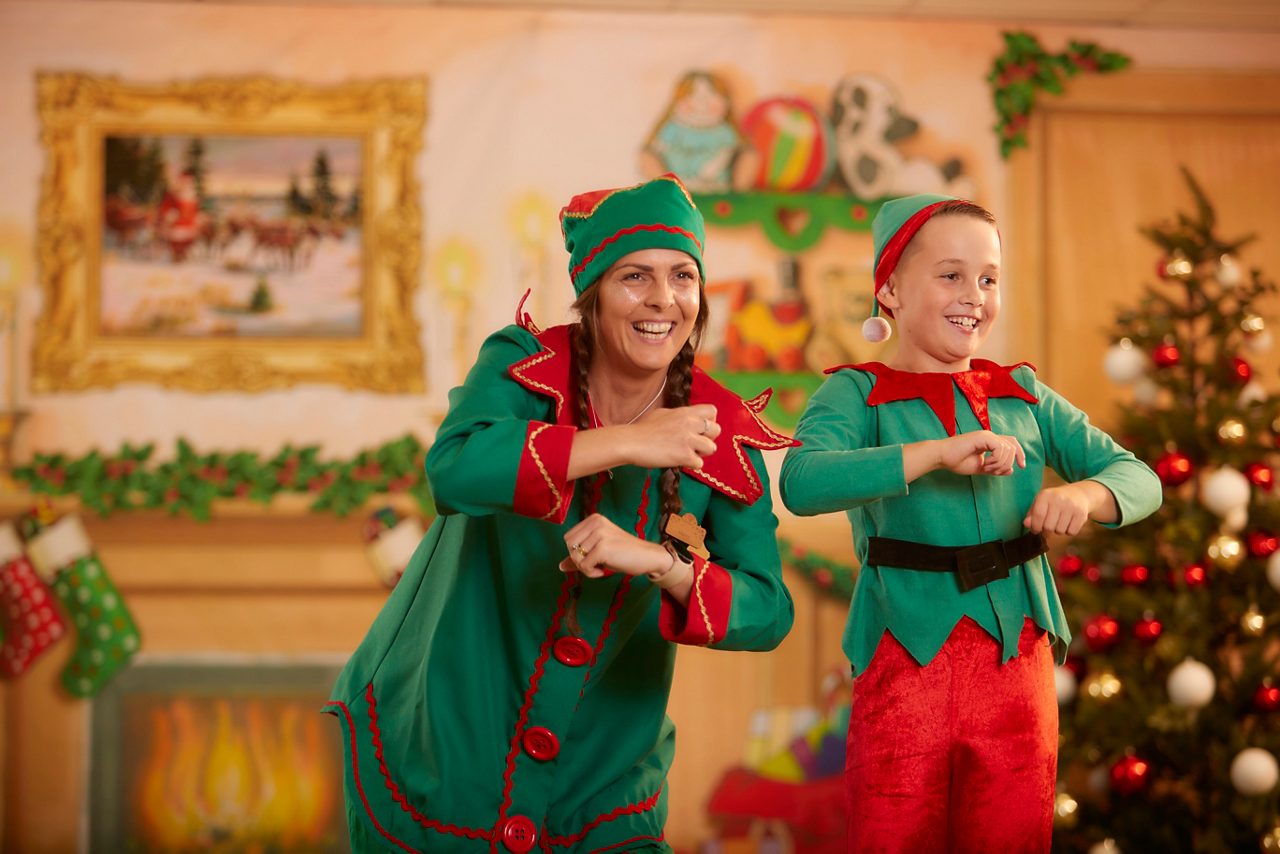 An elf dancing along with a young guest.