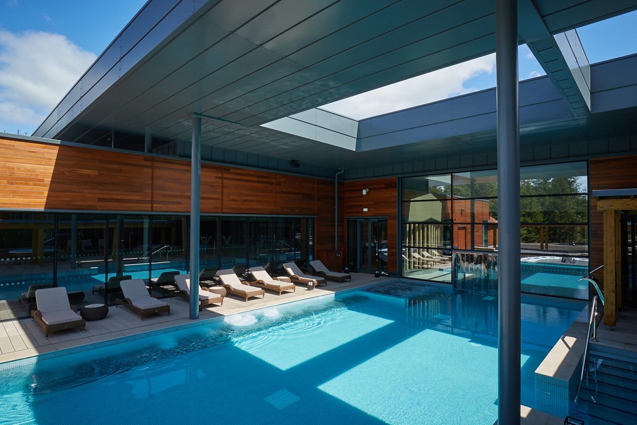 The sun reflecting on an Outdoor Pool surrounded by sun loungers.