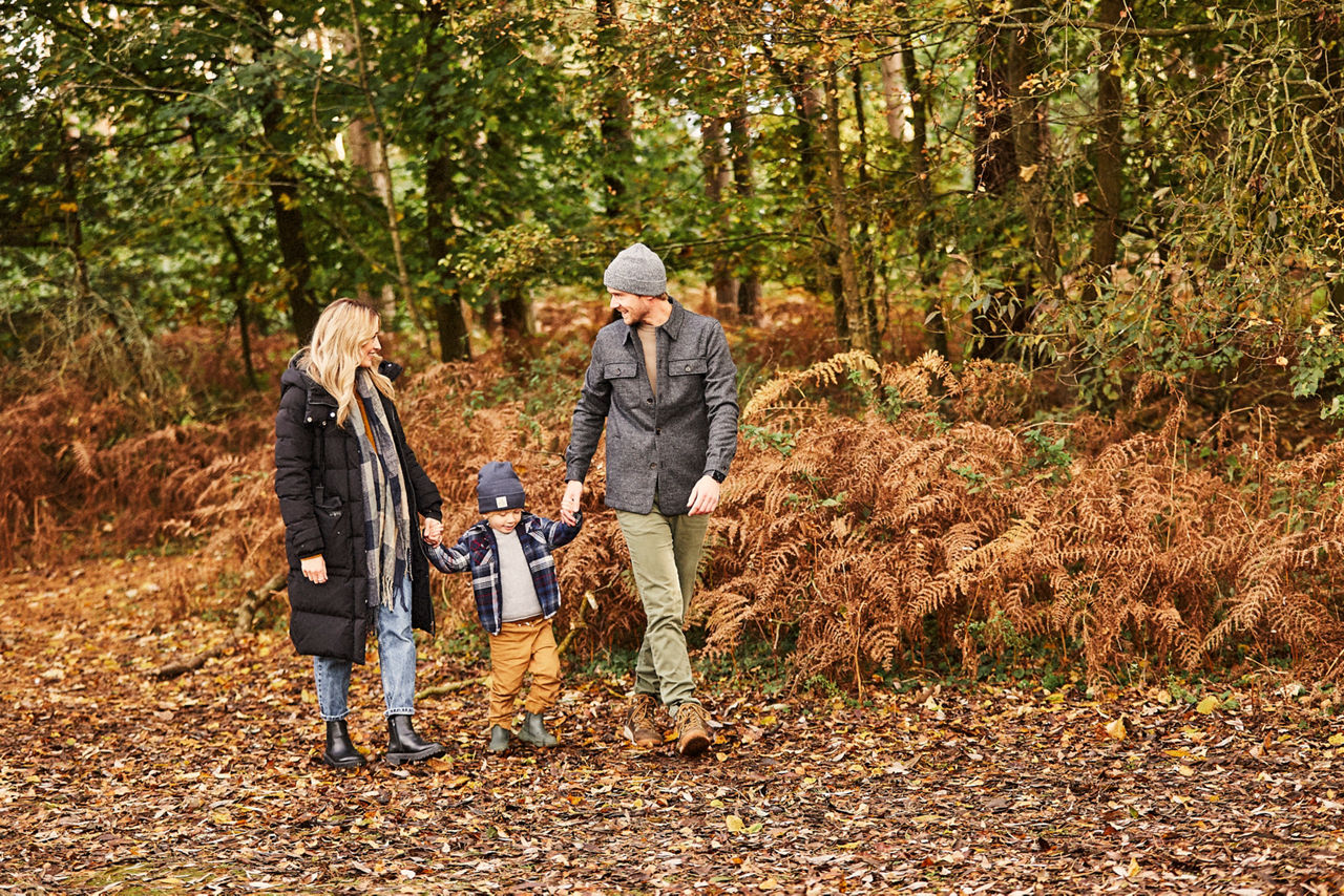A family on an autumnal woodland walk through the forest.