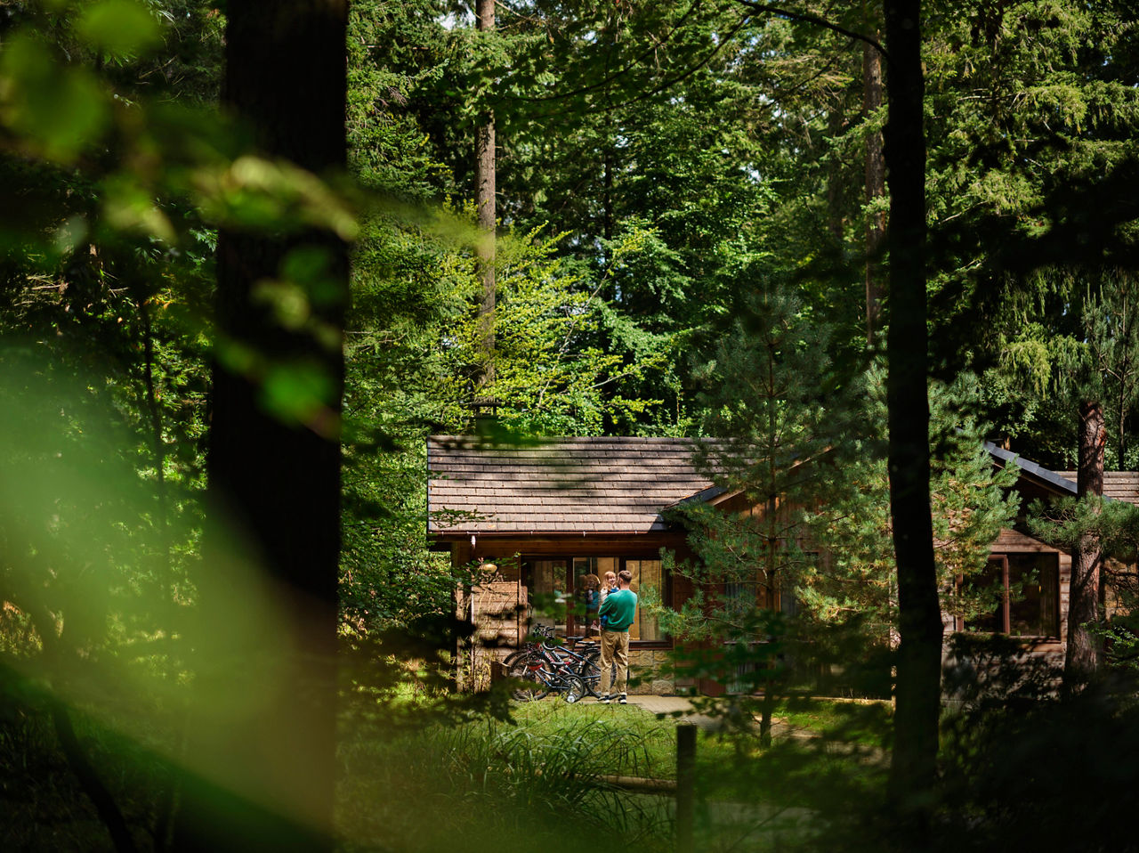 A father helping his child learn to ride a bike in the forest.