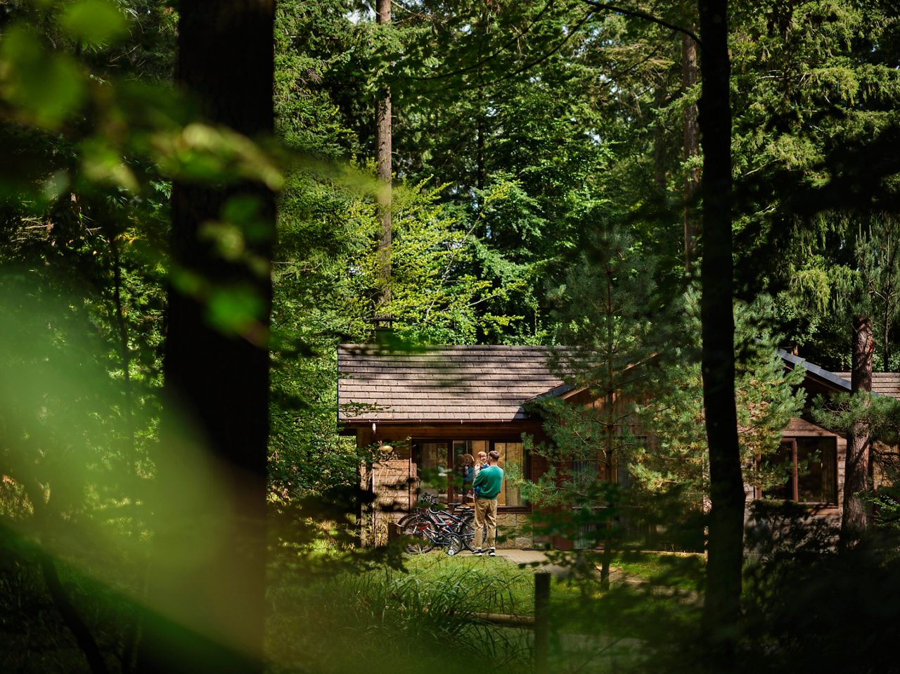 A father helping his child learn to ride a bike in the forest.