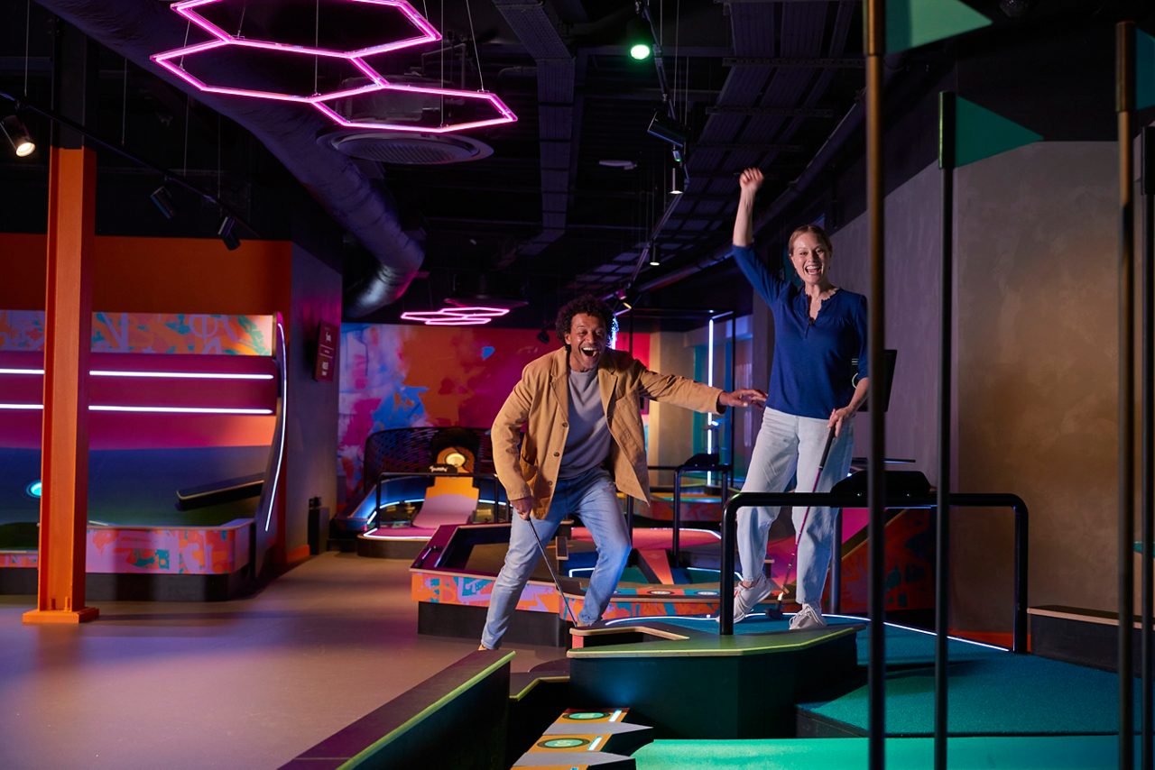 Two adults celebrating while playing puttify in the Entertainment Hive.