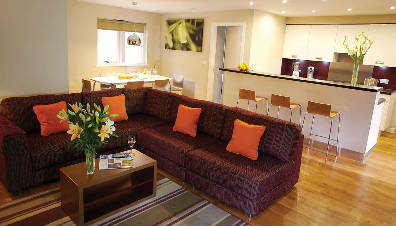 A corner sofa and bar style counter top in an Forest living and kitchen area