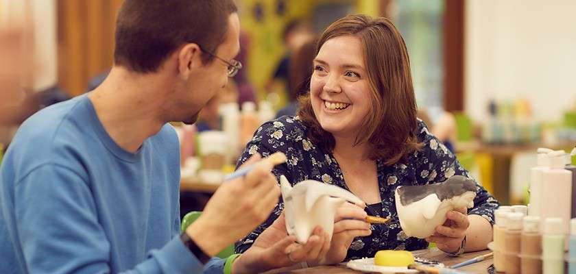 A couple doing pottery painting together.