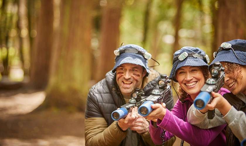 A family smiling and holding laser guns during our Laser Combat activity.