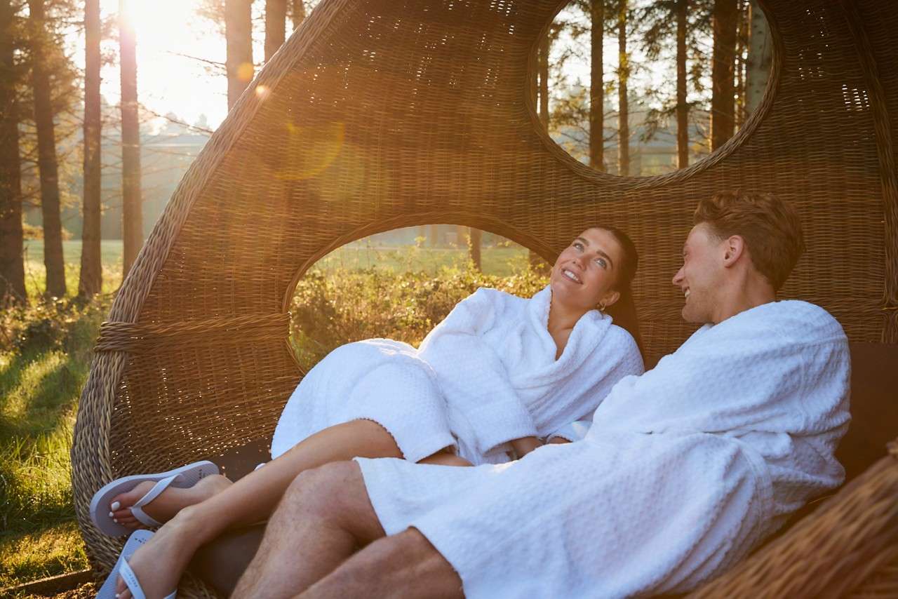 couple laid in lounge chair in forest awakening