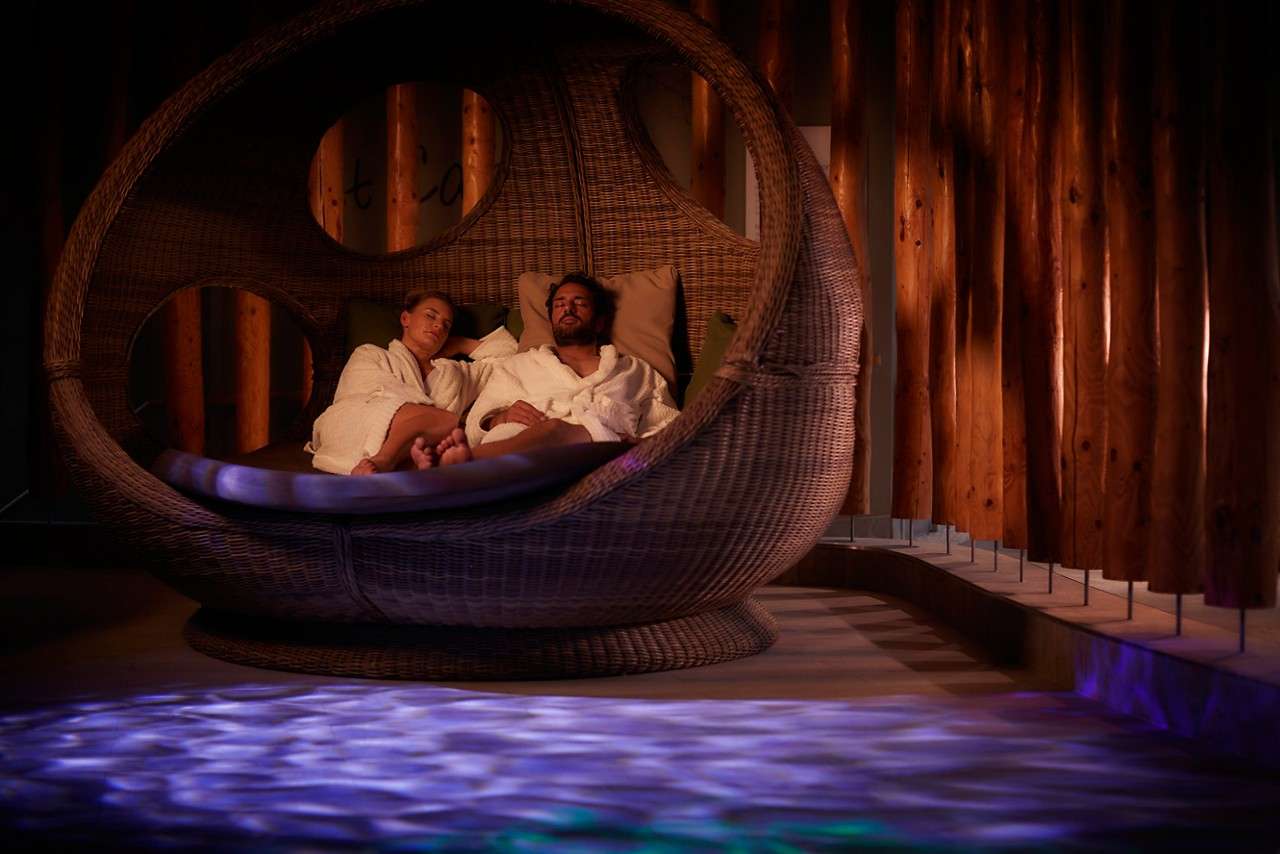 Couple sitting in a large seat in the Forest Nesting room.