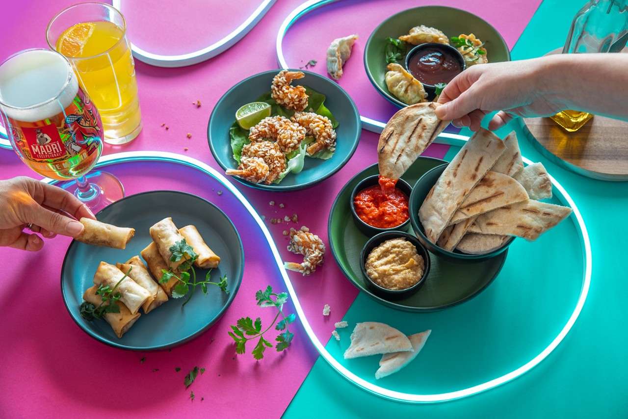 Selection of sharing dishes including, spring rolls, flatbread with dipping sauces and breaded prawns.