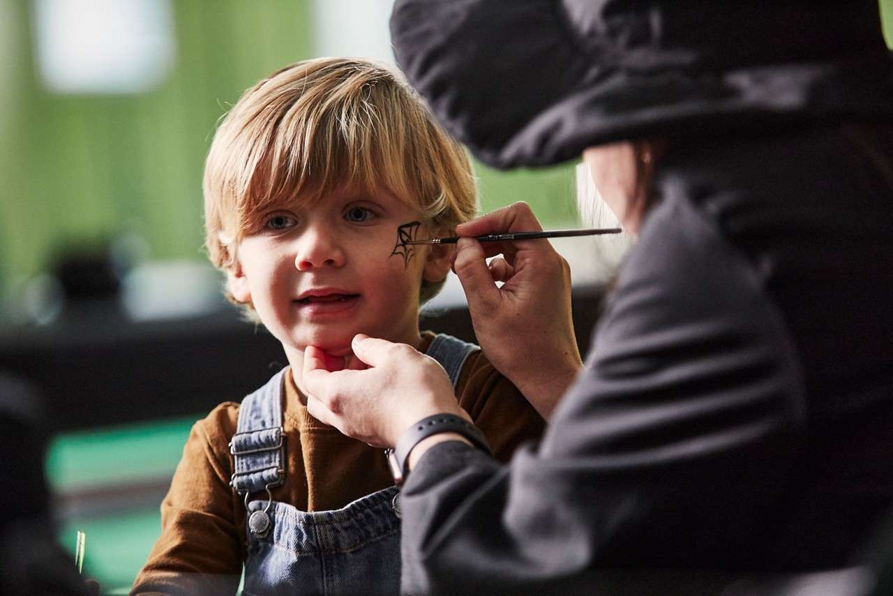 Young boy having his face painted.