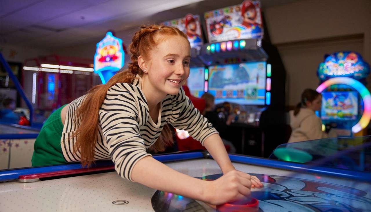 Teenage girl playing a game of air hockey