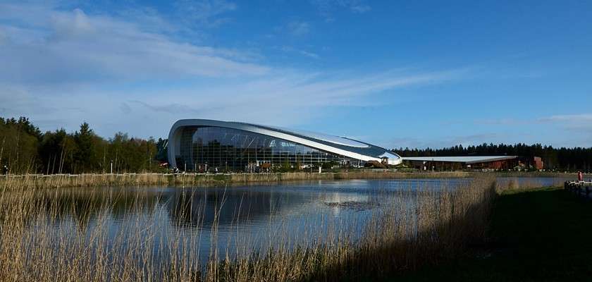 Curved building in front of the lake.