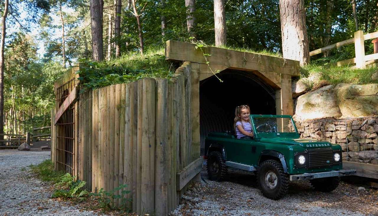 Young girl driving a little car through a tunnel.