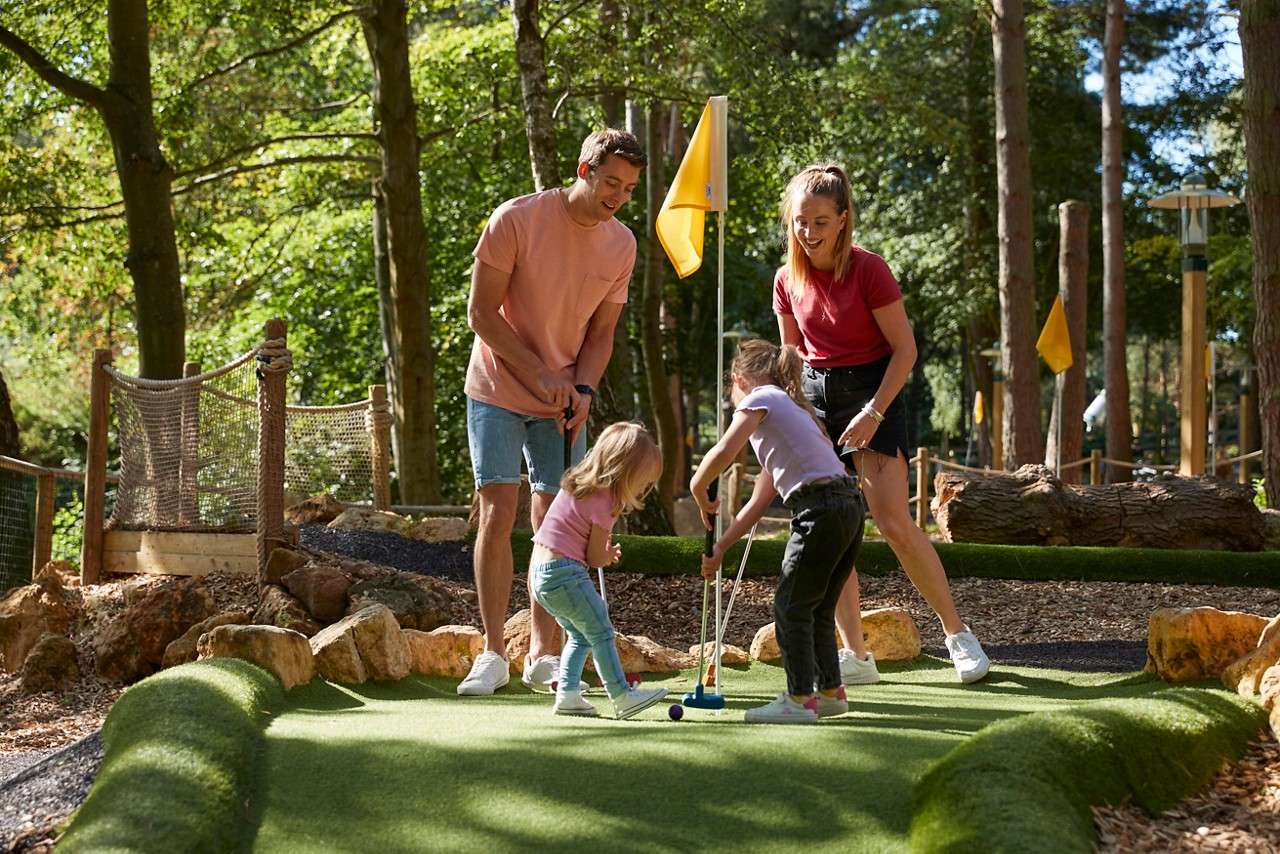 Family playing adventure golf on a course nestled in the forest.