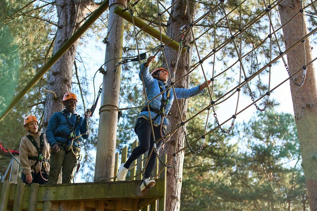 Woman stepping onto a rope bridge.