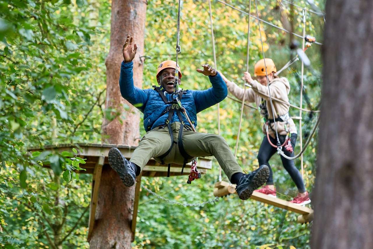Man zip lining between trees.