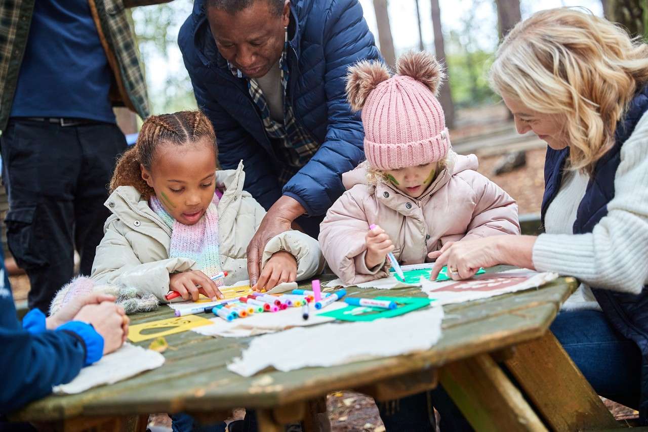 Two young people doing outdoor crafts with the support of some adults.
