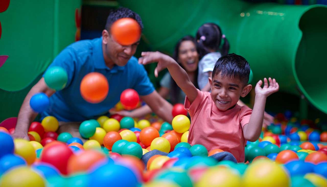 Young boy throwing plastic balls in a ball pit