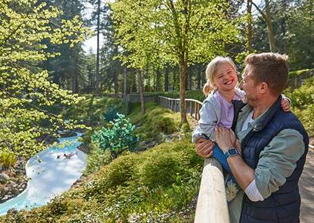 A toddler with her dad looking over the Wild Water Rapids. 
