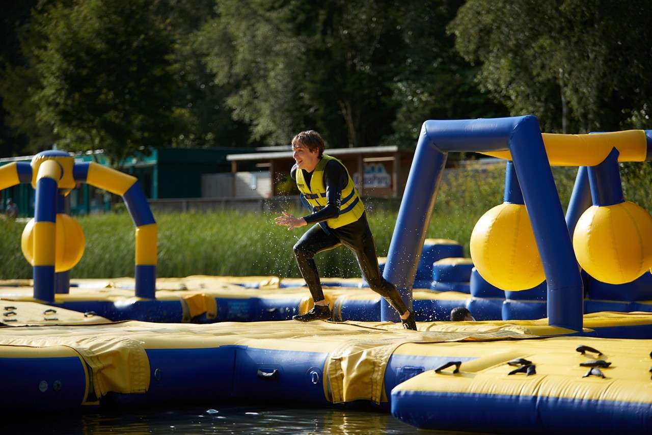 A teenage boy running across the inflatable Aqua Parc course.