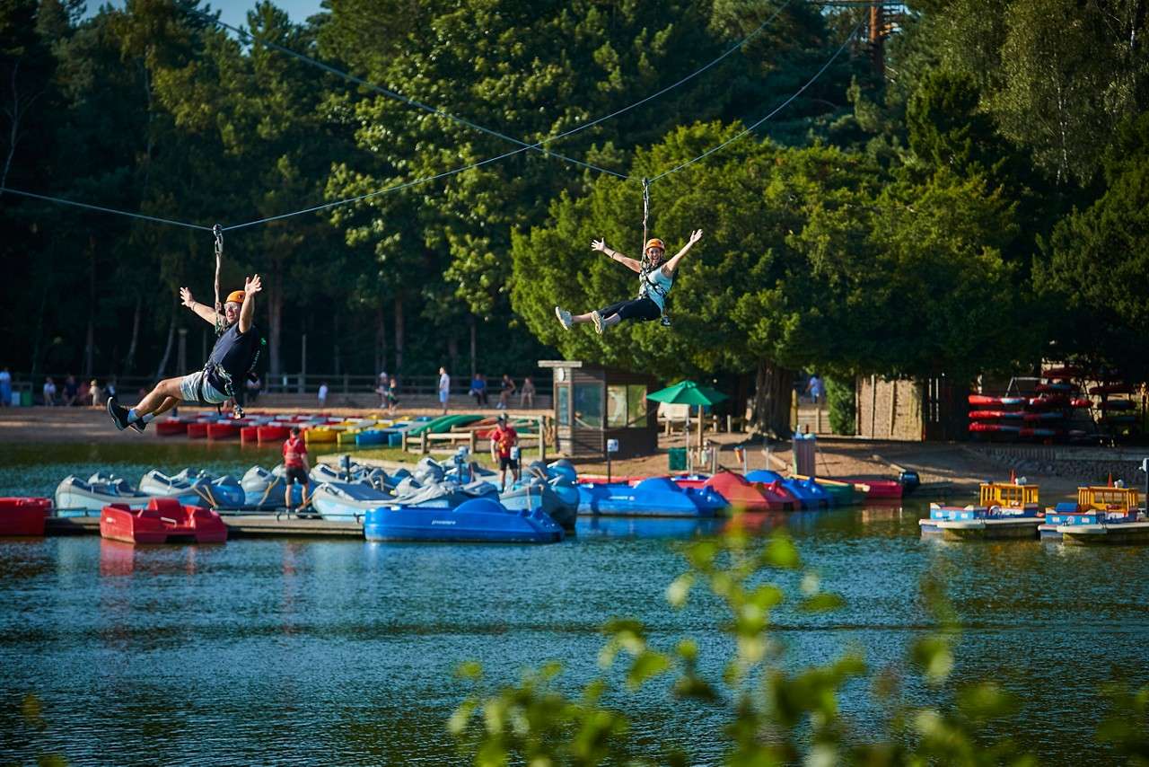 Two people zip lining over the lake.