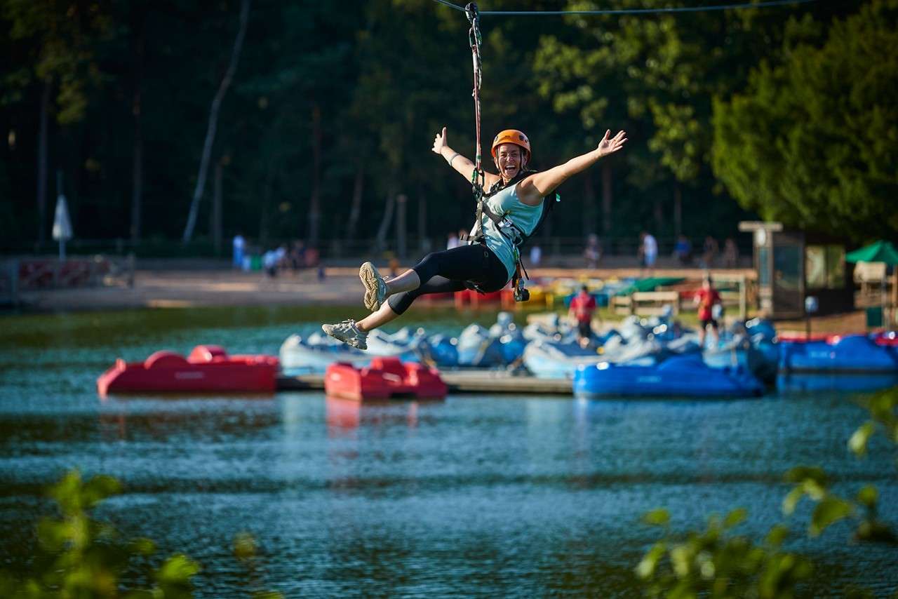Woman zip lining over the lake.