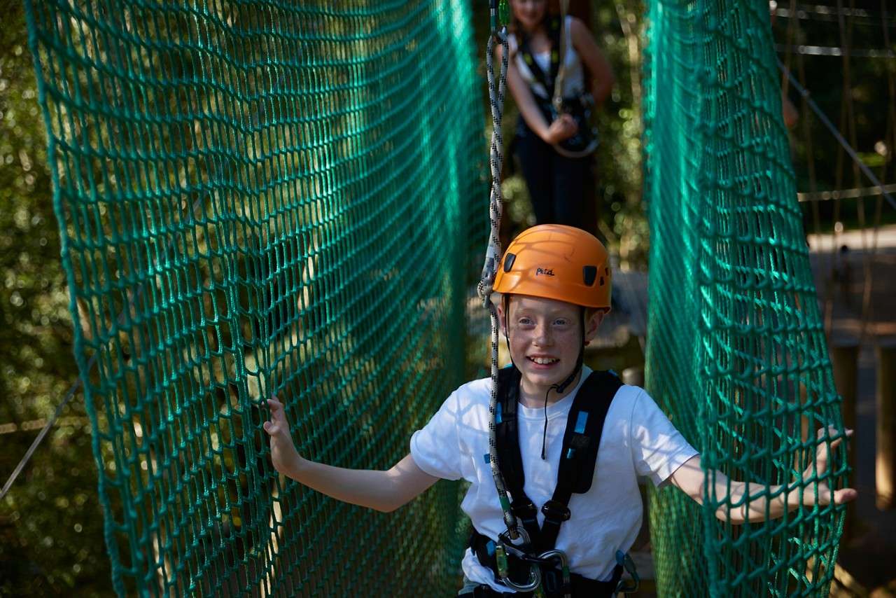 Young boy walking through a net bridge.
