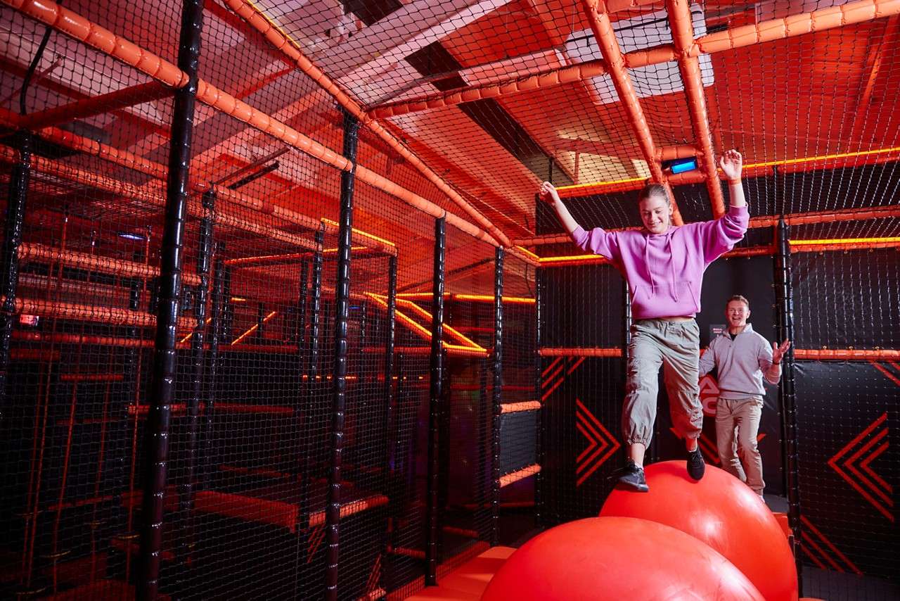 Young person jumping across giant balls inside the TAG Challenge Arena.