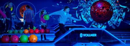 Bowler releases a ball while striding; other players wait nearby. Neon-lit bowling alley with colorful balls and a cosmic mural. Text: VOLLMER.