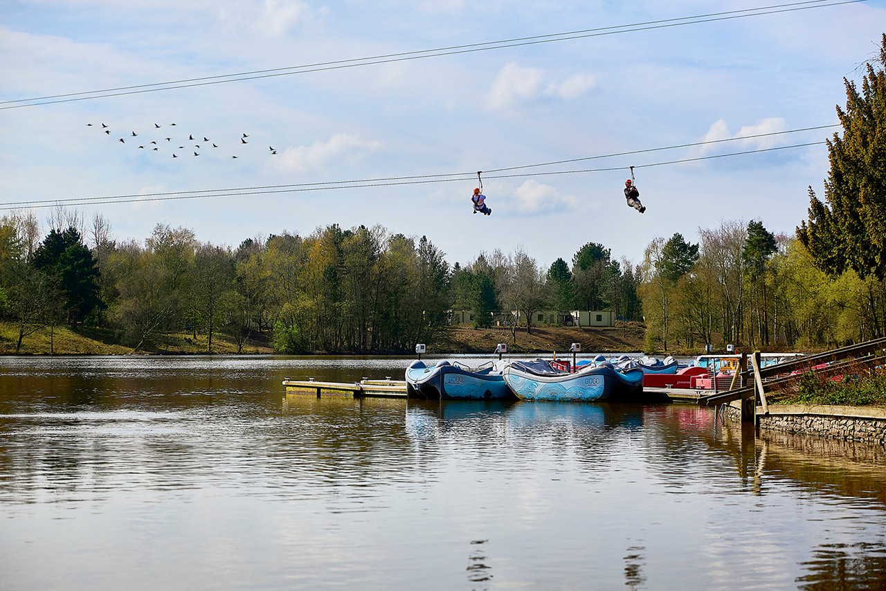 Two people on zip wiresd going over the lake.