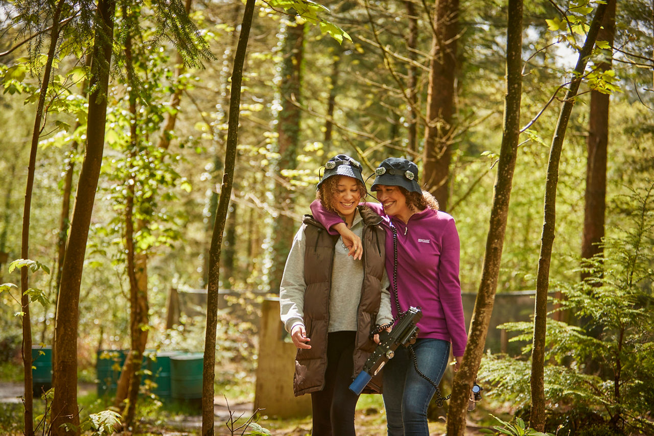 A mum with her arm round her daughter in the woodland during laser combat.
