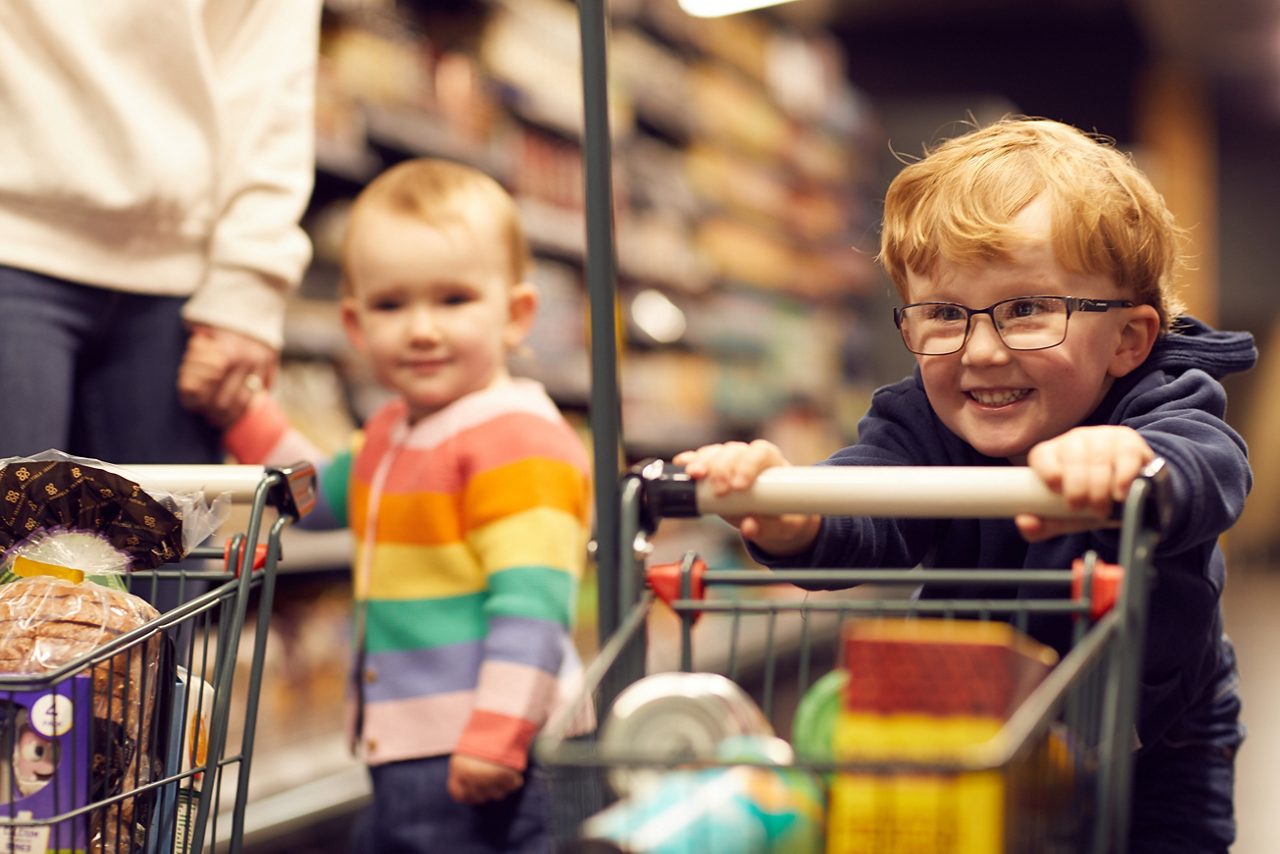 A little boy laughing and pushing a trolley through the ParcMarket.