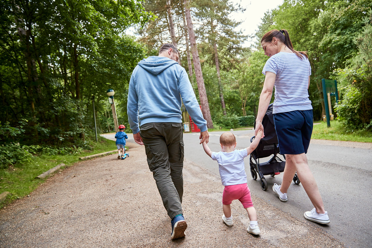 Family walking. Boy on scooter.