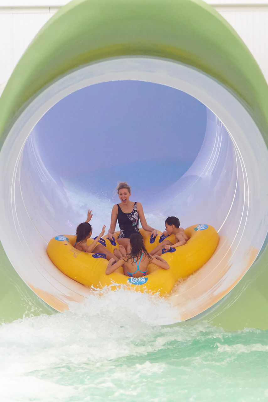 Family in an inflatable raft going down the Tropical Cyclone water slide.