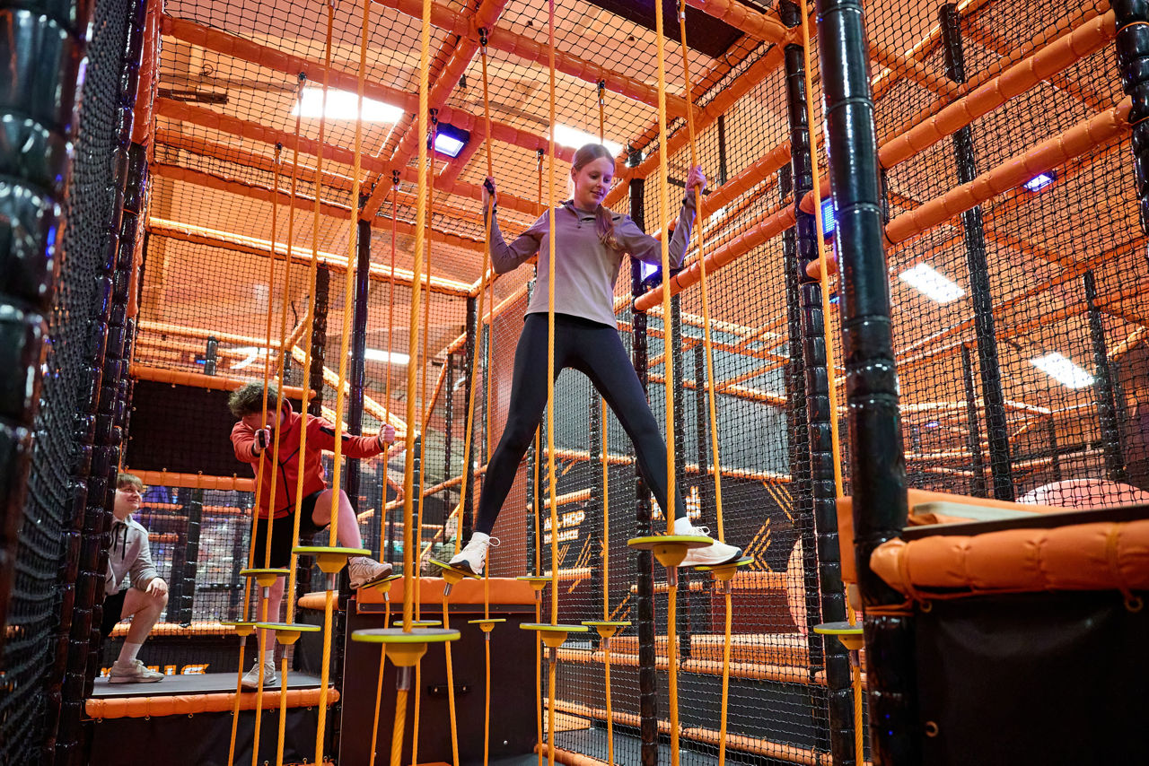 A teenager clmbing through the ropes in TAG Active.