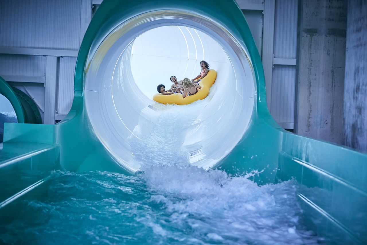 Family in an inflatable raft going down the Tropical Cyclone water slide.